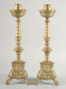 A GOOD PAIR OF 19TH CENTURY DUTCH BRASS CANDLESTICKS on triangular bases with claw and ball feet.
