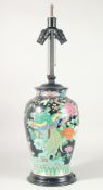 A CHINESE FAMILLE NOIRE PORCELAIN VASE on a wooden base. 16ins high.
