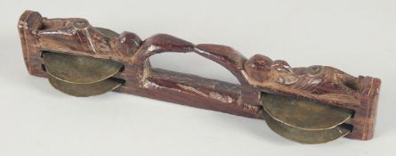 AN ISLAMIC CARVED WOOD MUSICAL HAND PIECE with four brass discs. 10.5ins high.