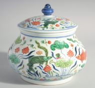 A CHINESE WUCAI PORCELAIN JAR AND COVER decorated with aquatic flora and fauna. 8ins high.