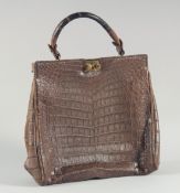 A 1940 - 1950 BROWN CROCODILE SKIN HANDBAG with fitted interior, brass mounts, lock and crocodile