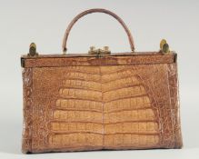 A 1940's - 1950's LARGE BROWN TWO COLOUR CROCODILE SKIN HANDBAG, with brass mounts and locks, raised