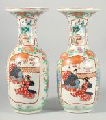 A PAIR OF JAPANESE IMARI VASES with panels of figures and flowers. 18.5ins high.