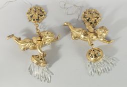 A PAIR OF GILT METAL CHERUB WALL LIGHTS with prism drops. 10ins long.