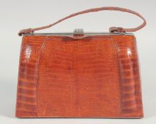 A 1930's - 1940's BROWN CROCODILE SKIN HANDBAG with chrome mounts, fitted suede interior and leather