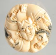 A CARVED BONE NETSUKE, faces. 1.5ins.
