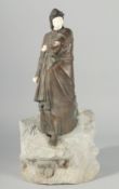 AN ART DECO DESIGN BRONZE AND BONE FIGURE STANDING ON A ROCK 18.5ins high.