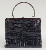 A 1940's - 1950's BLACK PATENT CROCODILE SKIN HANDBAG with fitted leather interior, brass mounts and