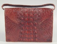 A 1940's - 1950's BROWN CROCODILE SKIN HANDBAG with round skin fold over flap, beige inside with a