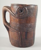 A GOOD CARVED WOOD TRIBAL MUG with handle carved from the solid. 8ins high.