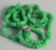A STRING OF CARVED JADE BEADS with gold clasp