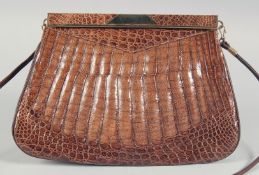 A 1930's - 1940's BROWN CROCODILE SKIN HANDBAG with gilt mount and suede fitted interior with long
