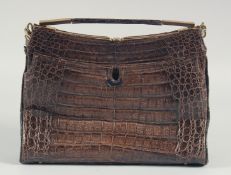 A 1940's - 1950's BROWN CROCODILE SKIN HANDBAG with brass mounts, outer flap, fitted leather
