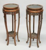 A PAIR OF CHINESE REDWOOD CIRCULAR STANDS with hardwood inset tops. 2ft 9ins high x 1t 1ins
