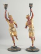 A PAIR OF PAINTED AND GILDED EASTERN FIGURE CANDLESTICKS of Arabs on bases. 16ins high.