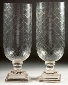 A PAIR OF SLICE CUT GLASS STORM LAMPS on square stepped bases. 15ins high.