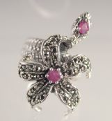 A SILVER AND MARCASITE RUBY SET SNAKE AND FLOWER RING.