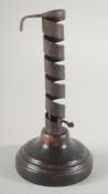AN EARLY IRON CANDLESTICK on a circular wooden base. 8ins high.