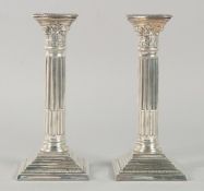 A PAIR OF SILVER PLATE CORINTHIAN COLUMN CANDLESTICKS 8ins high.