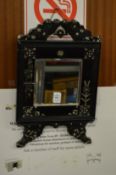 A small mirror with ebonised frame.