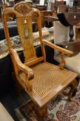 A large Continental walnut open armchair with carved decoration and canework seat.
