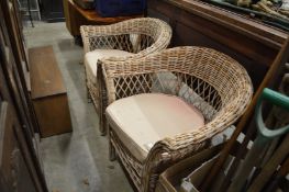 A pair of wicker armchairs.
