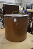 A large copper twin handled cooking pot with lid.