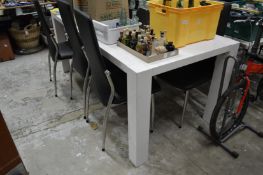 A modern white lacquer table and six dining chairs.