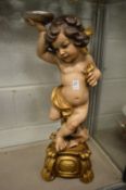 A carved painted and gilded model of a cherub.