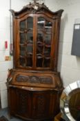 A Continental oak corner cupboard with profusely carved decoration, the upper section with glazed