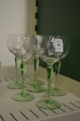A set of six green stemmed drinking glasses.