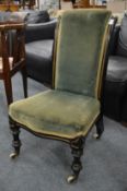 A Victorian ebonised nursing chair with green velour upholstery.