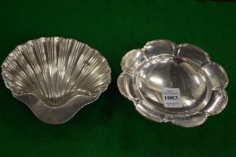 A small silver dish and a silver shell shaped dish.
