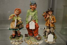 A pair of Capodimonte figures of a boy and girl together with another figure.