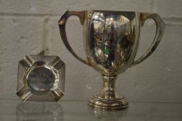 A silver twin handled trophy cup and an ashtray.