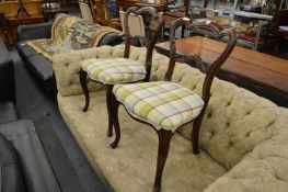 A pair of Victorian carved rosewood dining chairs with overstuffed seats on carved cabriole legs.