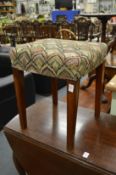 An upholstered mahogany framed stool on tapering square legs.
