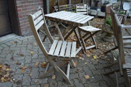 A folding wooden garden table and pair of chairs.