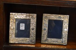 A pair of small silver photograph frames with embossed decoration.