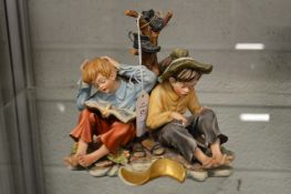 A Capodimonte figure group of two children by a tree stump.