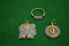 A platinum and 9ct gold three stone ring and two jade pendants.