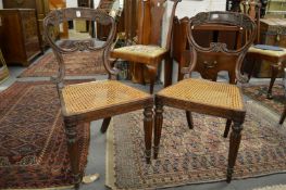 A pair of 19th century simulated rosewood dining chairs with carved backs and canework seats on