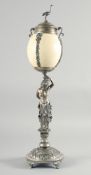 A GOOD CONTINENTAL SILVER MOUNTED EMU EGG mounted as large cup and cover, held by a classical female