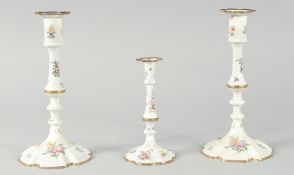 A PAIR OF BILSTON ENAMEL CANDLESTICKS painted with flowers. 9.5ins high and another smaller, 6.