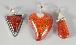 THREE SILVER AND AMBER PENDANTS.