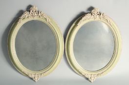 A PAIR OF PAINTED OVAL MIRRORS with applied fruiting vines. 1ft 9ins high, 1ft 4ins wide.
