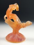 A DAUM COLOURED GLASS MONKEY on a branch with a circular base. Signed, Daum, France. 5ins high.
