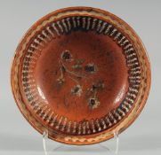 A DUTCH TERRACOTTA CIRCULAR DISH painted with flowers. 13ins diameter.
