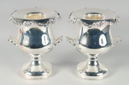 A GOOD PAIR OF SILVER PLATED TWO HANDLED URN SHAPED WINE COOLERS on circular bases. 12ins high.