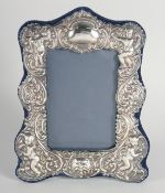 A LARGE SILVER UPRIGHT PHOTOGRAPH FRAME with cupids and masks. 9ins x 6.5ins.